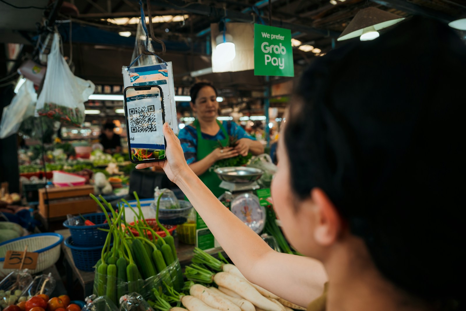 a woman holding up a smart phone in a market